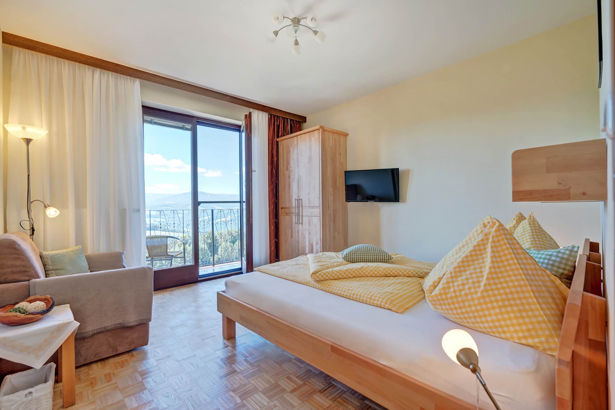Bright bedroom with bed, sofa, wardrobe and balcony with view.
