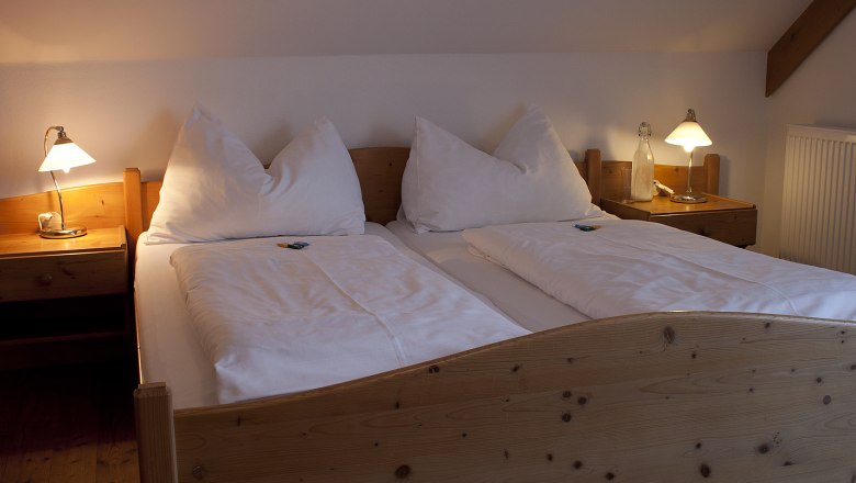 Comfortable double bed in a country inn room with wooden frame and bedside tables, illuminated by two table lamps.