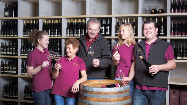 Five people in a wine cellar clink glasses.