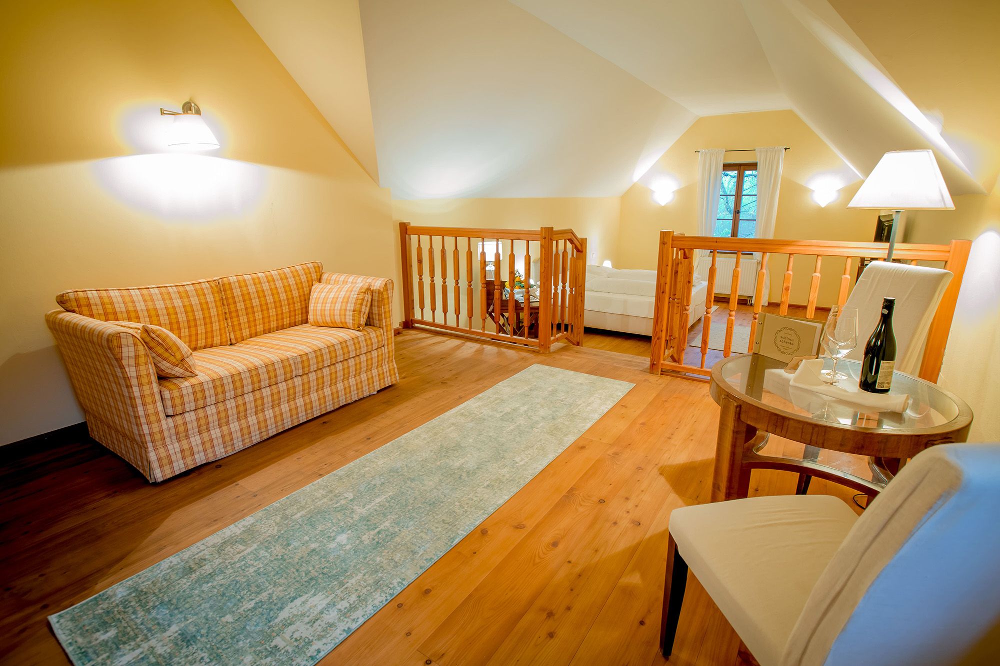 Cozy room with sofa, table and chair, wooden floor and railings.