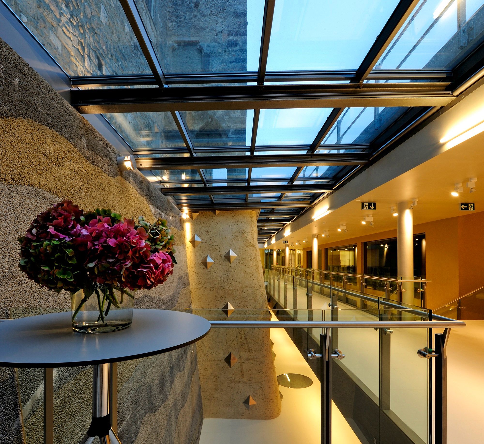 Modern vestibule of BURG Perchtoldsdorf with glass roof and flower arrangement.