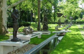 Sculpture garden with several bronze figures and a watercourse.