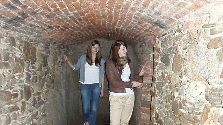 Two women in a narrow, brick-built tunnel with a tiled ceiling.