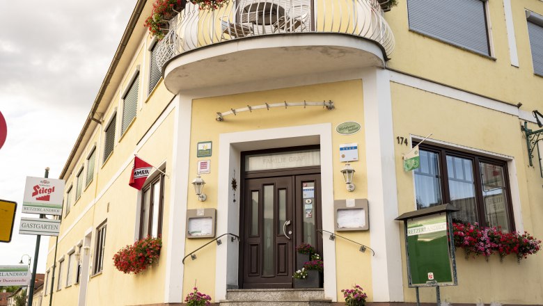 Yellow pub with flowers and signs, including "Stiegl" and "Retzerlandhof".