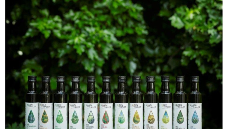 A row of oil bottles from Hagenthaler &Ouml;lmanufaktur in front of green foliage.