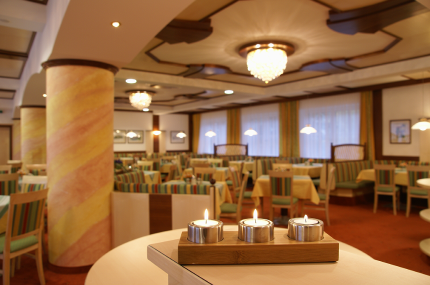 An elegant hotel room with laid tables, chandeliers and candles on a table in the foreground.