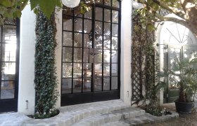 Entrance area with large glass windows, ivy and paving stones.
