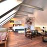 Modern bedroom in the attic with wooden floor, bed, armchairs and decorative room divider.