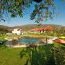 Garden area with pond, sun loungers and parasols, surrounded by buildings and hills.