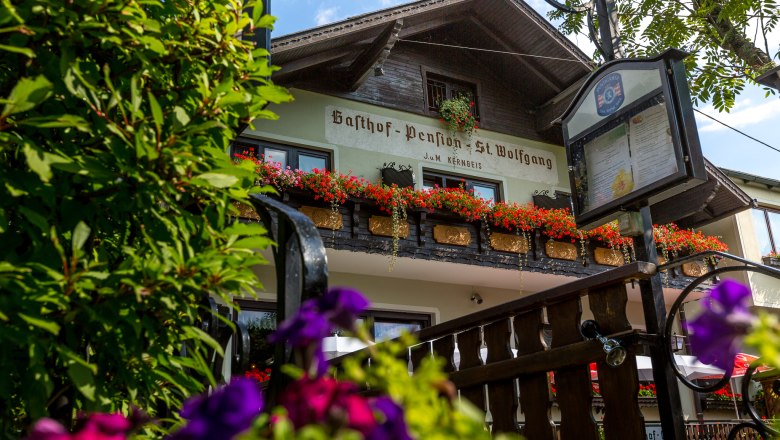 Gasthof Pension St. Wolfgang with a balcony decorated with flowers and a sign in the foreground.