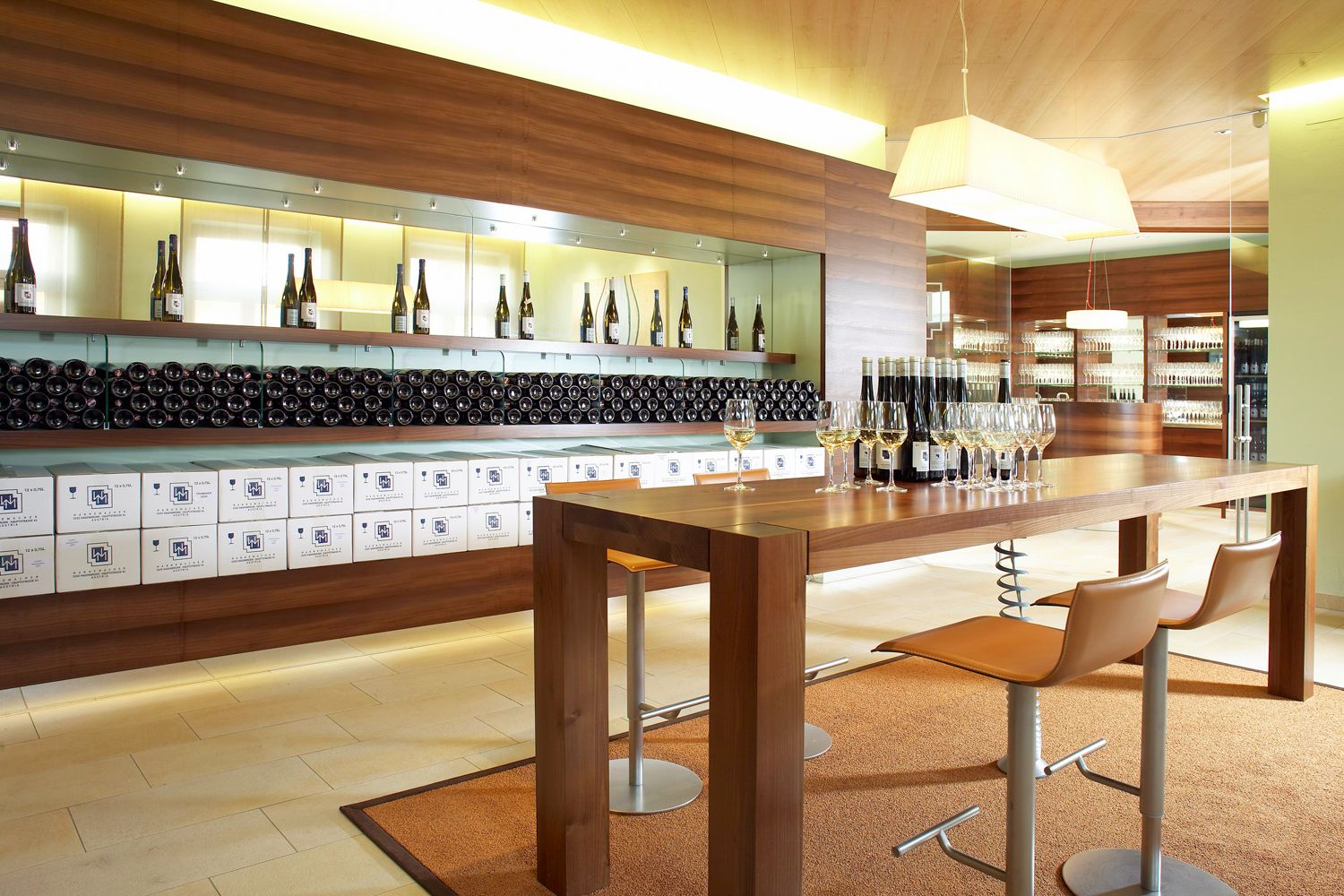 Modern tasting room with wooden table, wine glasses and wine bottles.