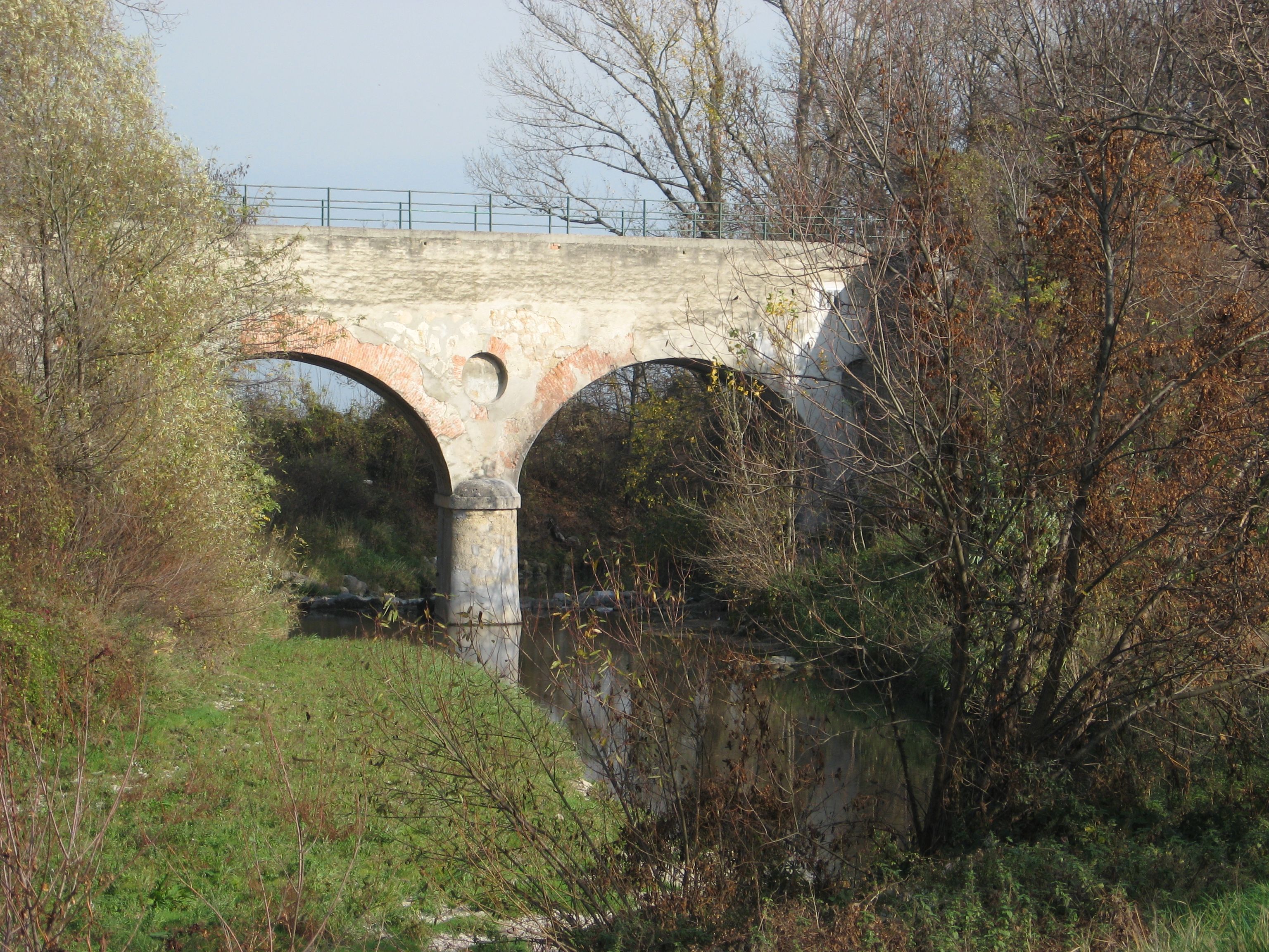 Old stone bridge over a small river, surrounded by trees in the fall.