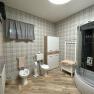 Modern bathroom with shower cubicle, bidet, toilet and cupboard on wooden floor.