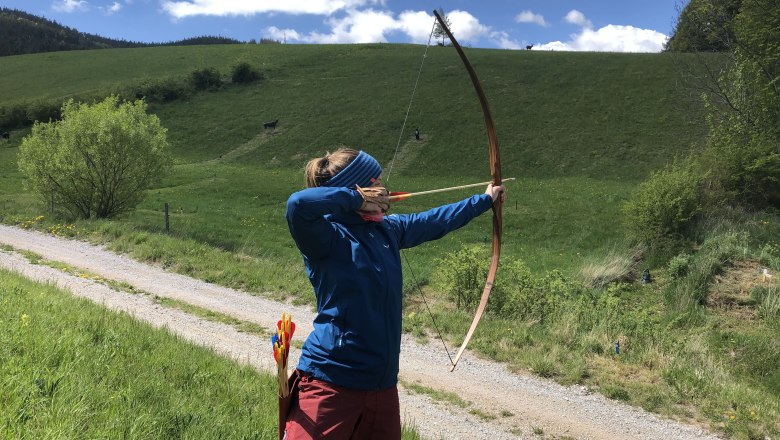 Person shoots with a bow in a field.