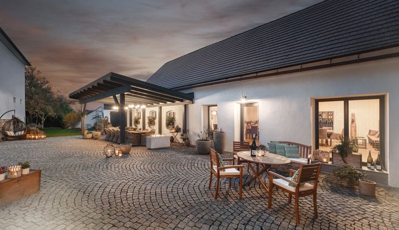 Paved courtyard with tables and chairs, surrounded by buildings at dusk.