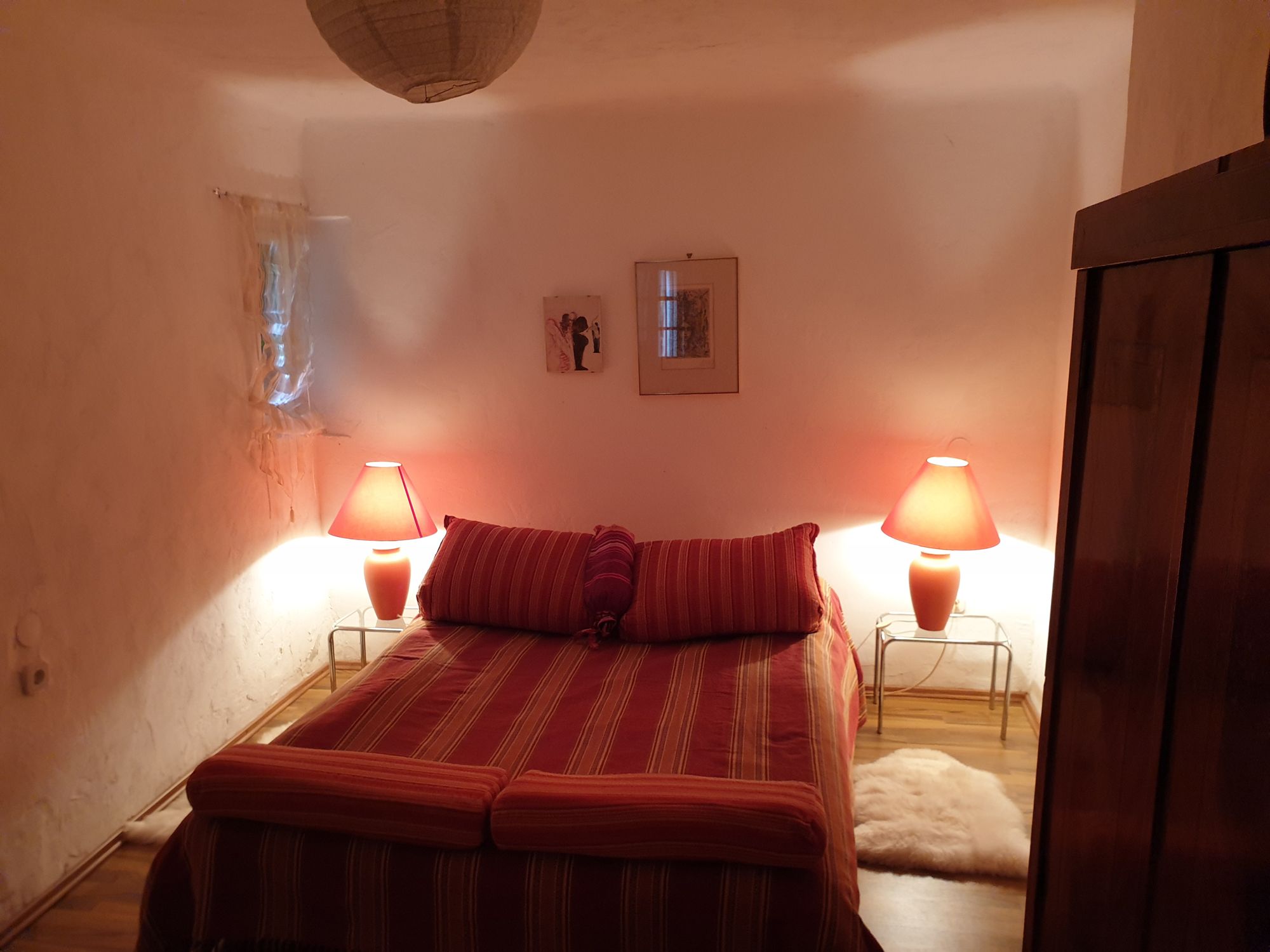 Cozy bedroom with double bed, red lamps and wooden furniture.