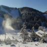 Snowy landscape with ski resort and sun in the background.