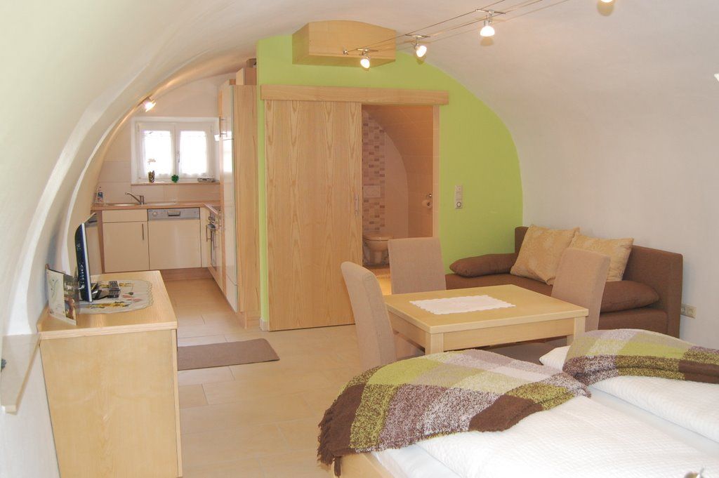 Cozy apartment with vaulted ceiling, kitchen, dining table, sofa and bed.