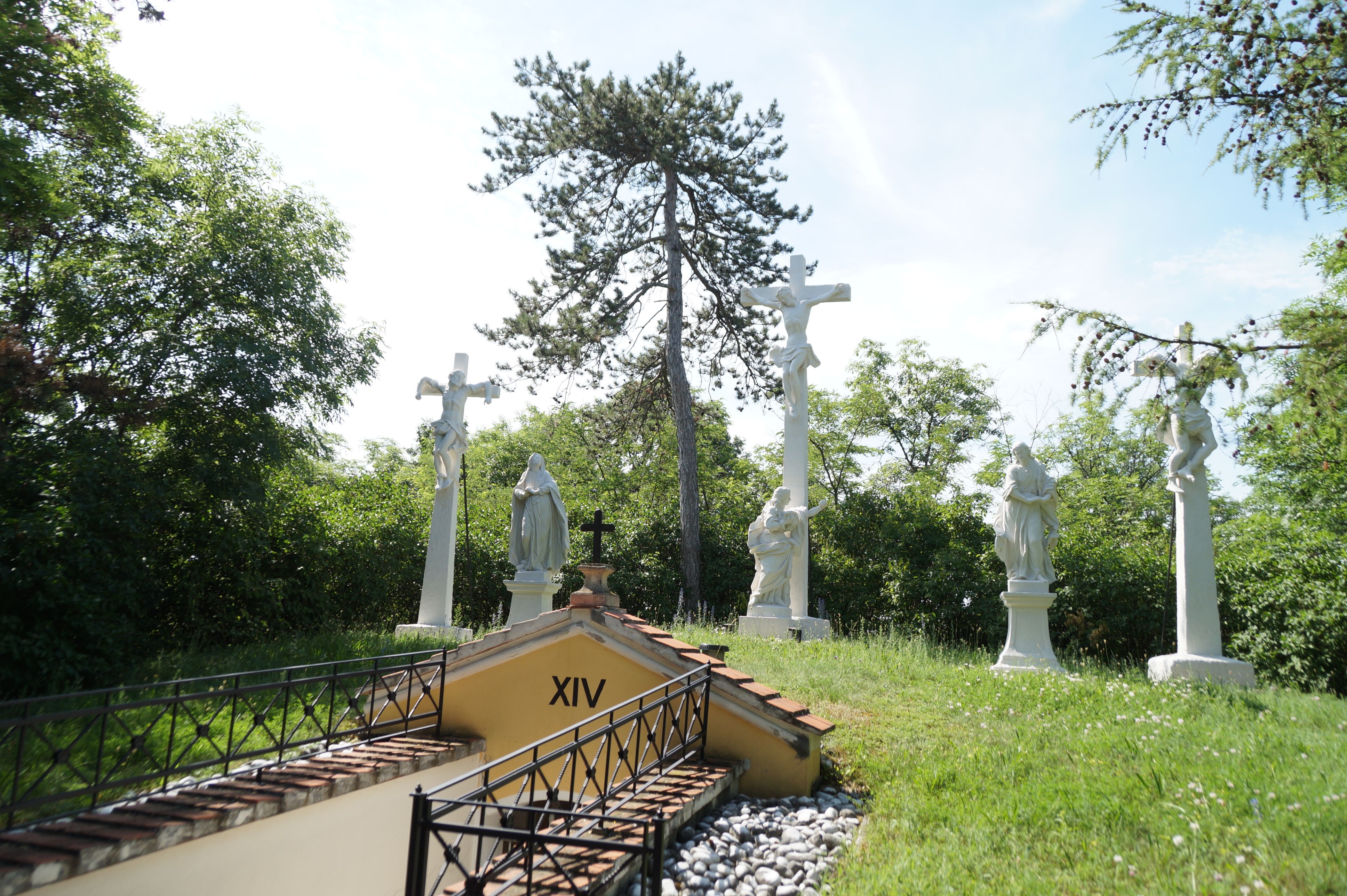 Station of the Cross with several white statues and a cross outside.
