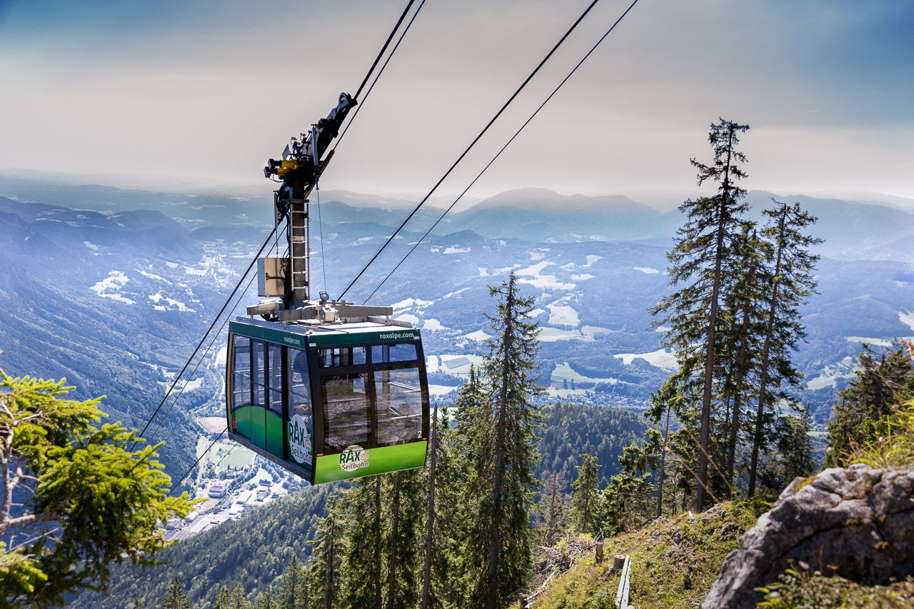 Cable car in the mountains with views of wooded slopes and valleys.