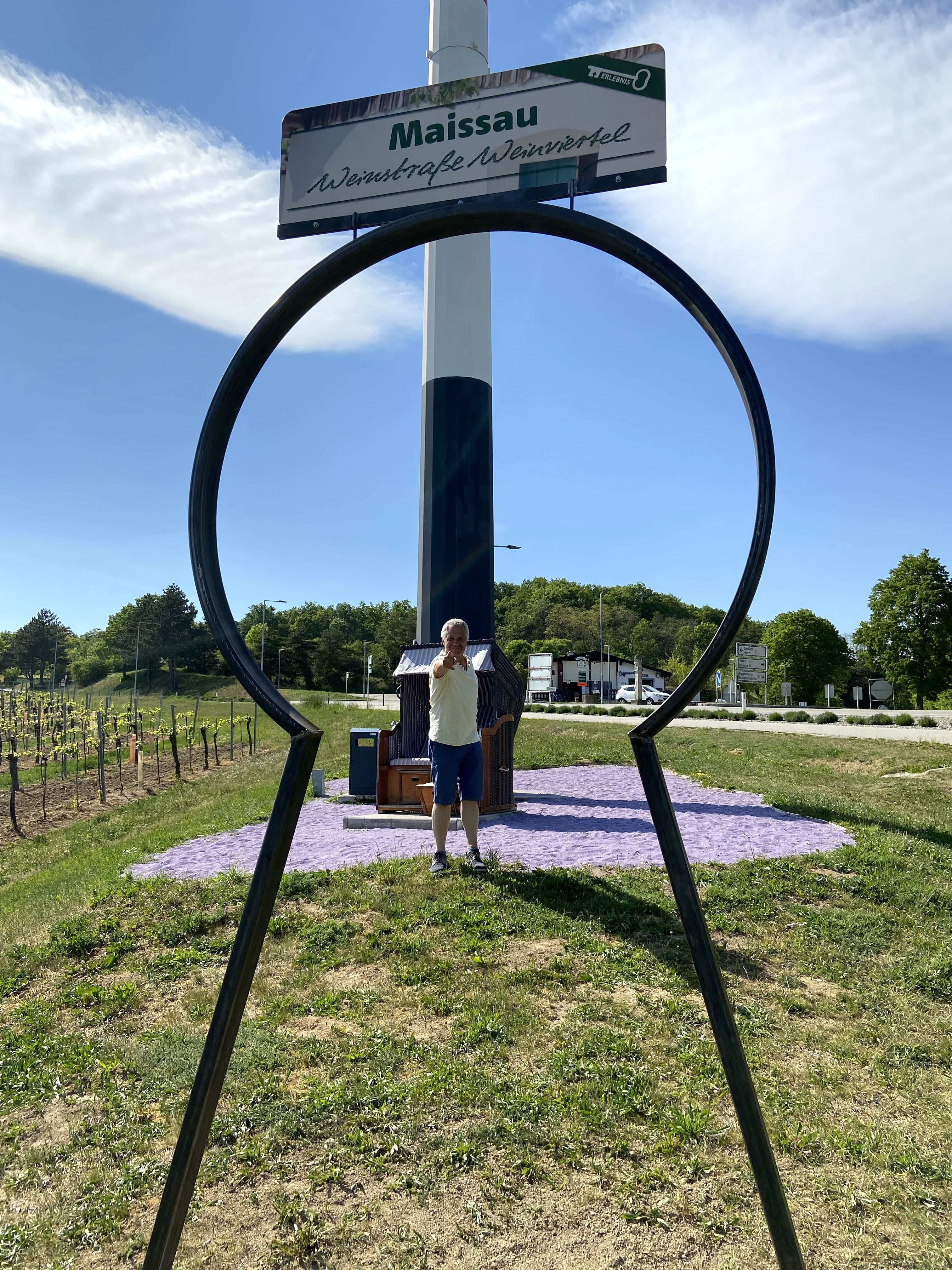 A man stands behind a large key shape in Maissau, with a sign for the Wine Road Weinviertel in the background.