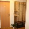 Entrance area with wooden door, wooden coat rack with hooks, bench and plant.