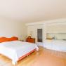 Bright bedroom with double bed, wooden furniture and small kitchenette.