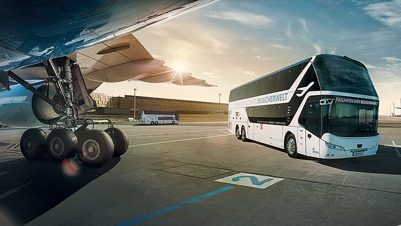 A bus stands next to an airplane on the tarmac at Vienna Airport.