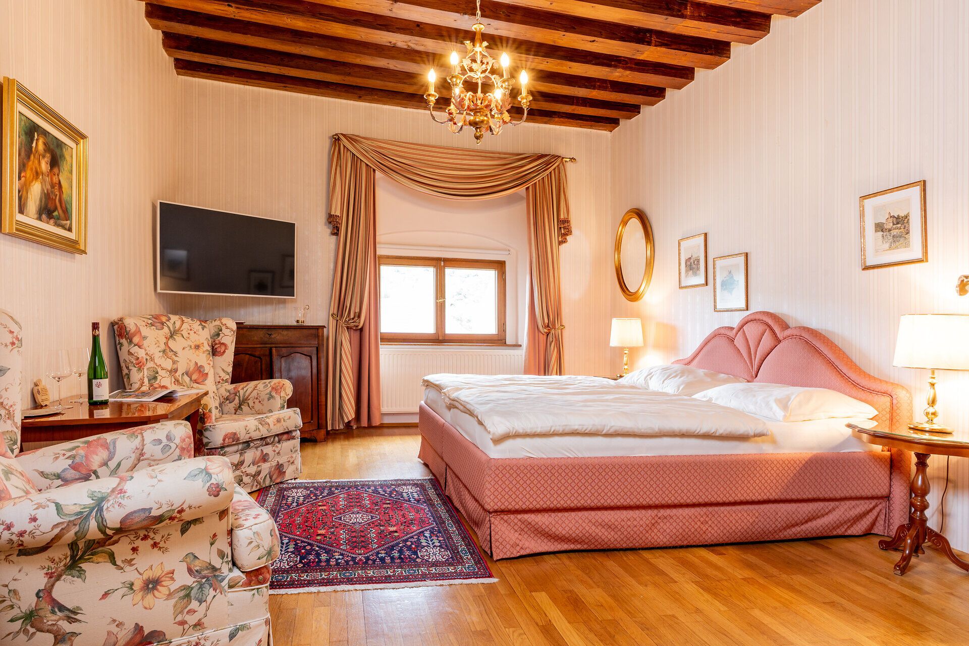 In einem eleganten Zimmer mit einem Hauch von Nostalgie lädt die gemütliche Atmosphäre zum Entspannen ein. Die warmen Holztöne und die stilvolle Einrichtung schaffen einen perfekten Rückzugsort, um die Schönheit der Umgebung zu genießen.