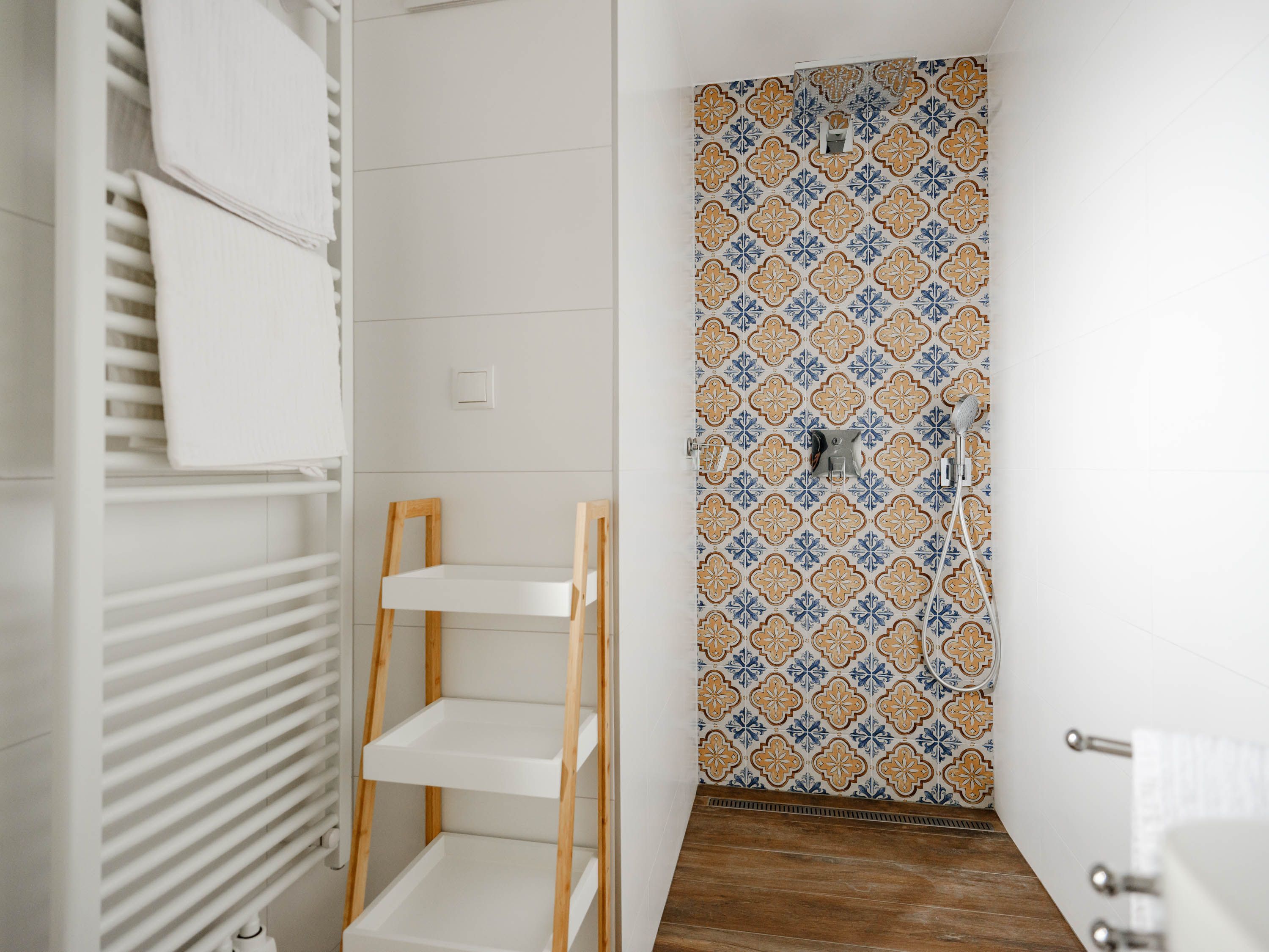 Modern bathroom with patterned tiles in the shower, towel rail and shelf.