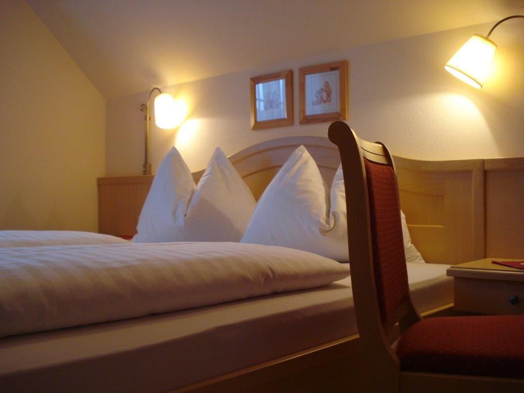 Cozy guest room with double bed, two bedside lamps and a chair.