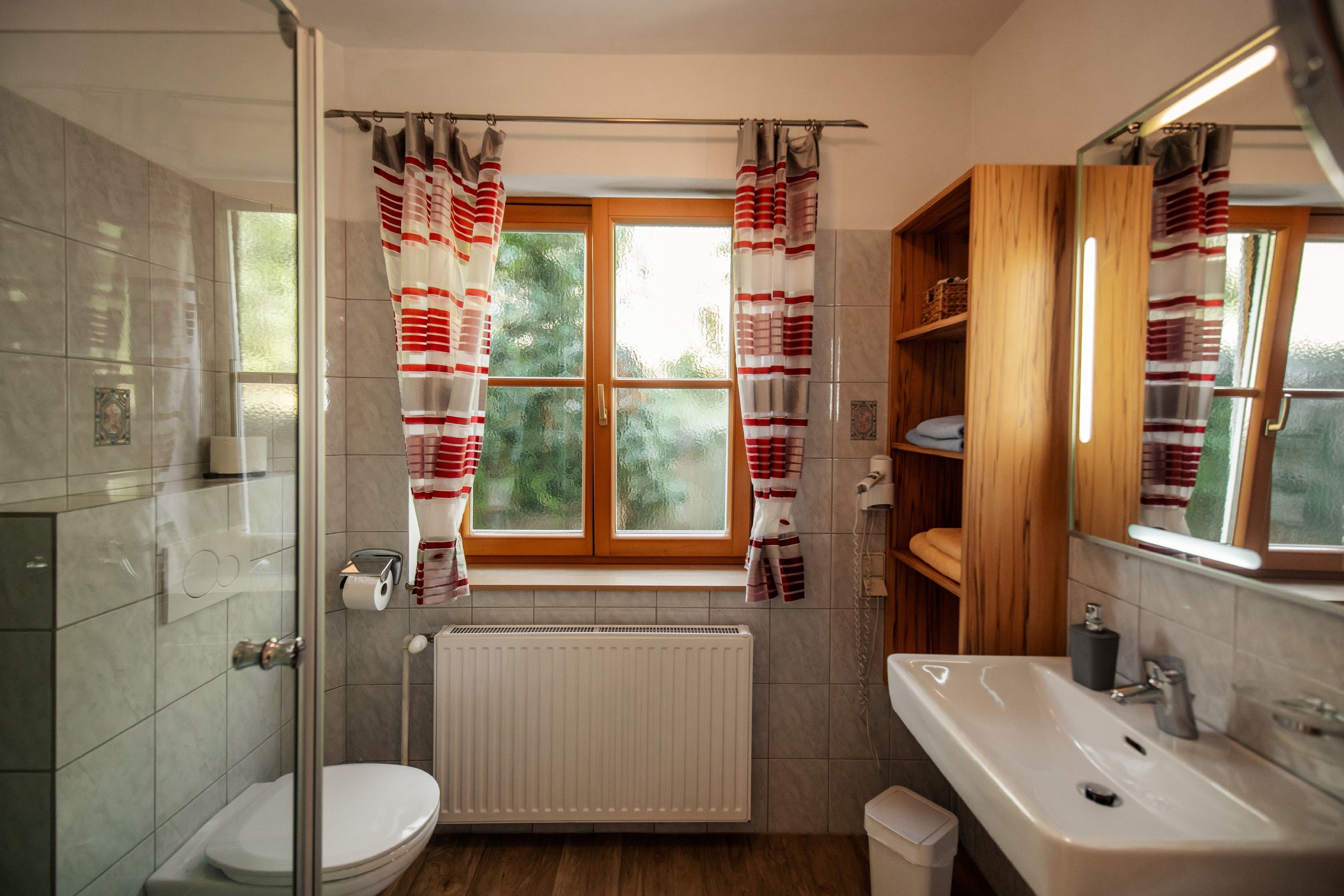 Modern bathroom with window, shower cubicle, washbasin and shelves.