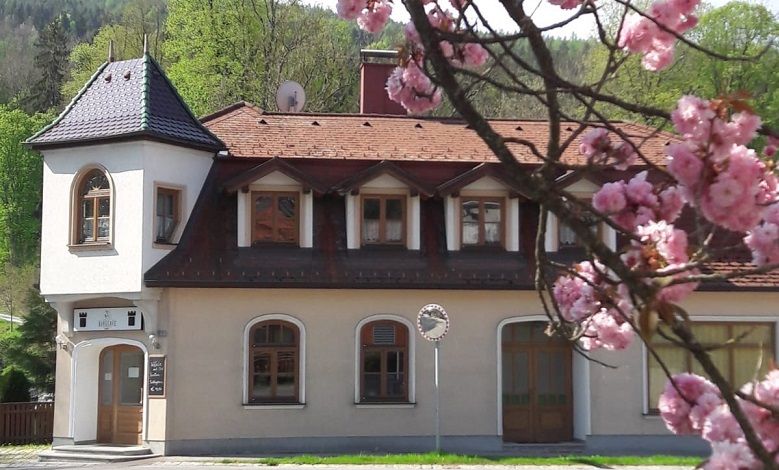 A two-storey building with a tower and blooming cherry blossoms in the foreground.