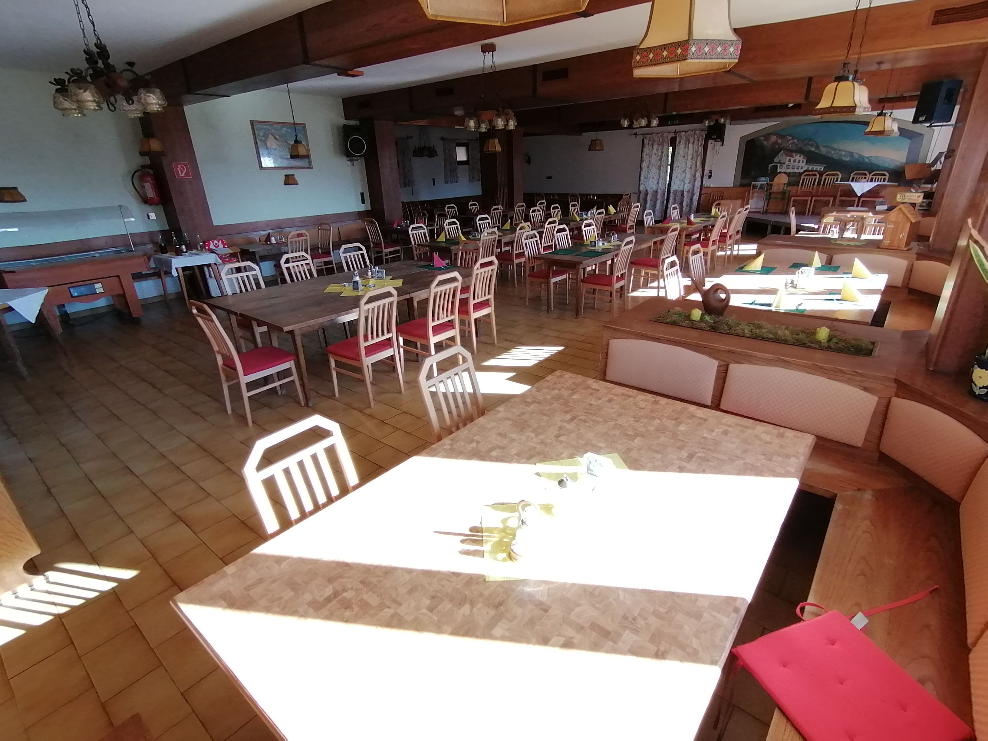 An empty dining room with wooden tables and red chairs at Gasthof Mohr.