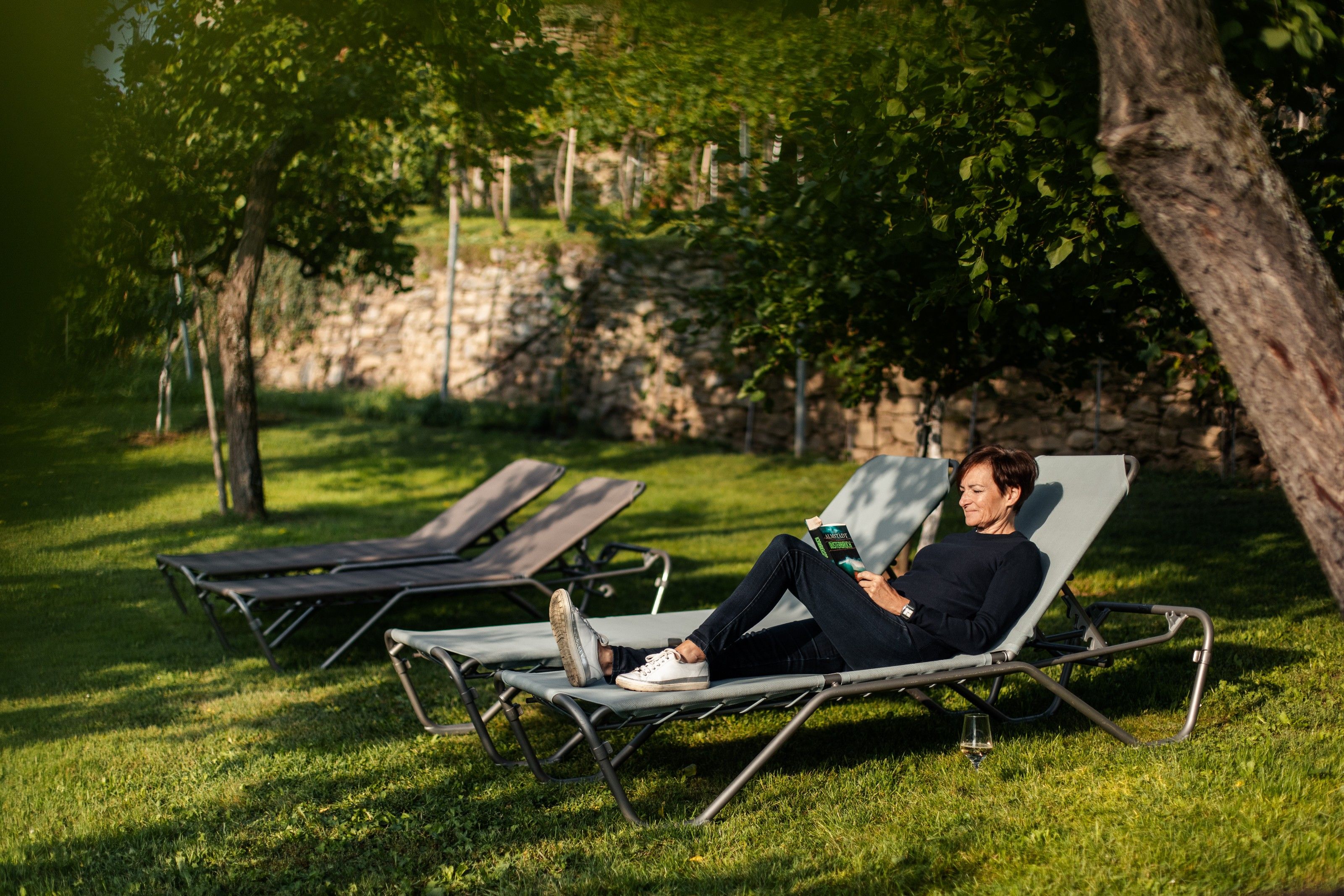 Person reads on a sun lounger in the garden.