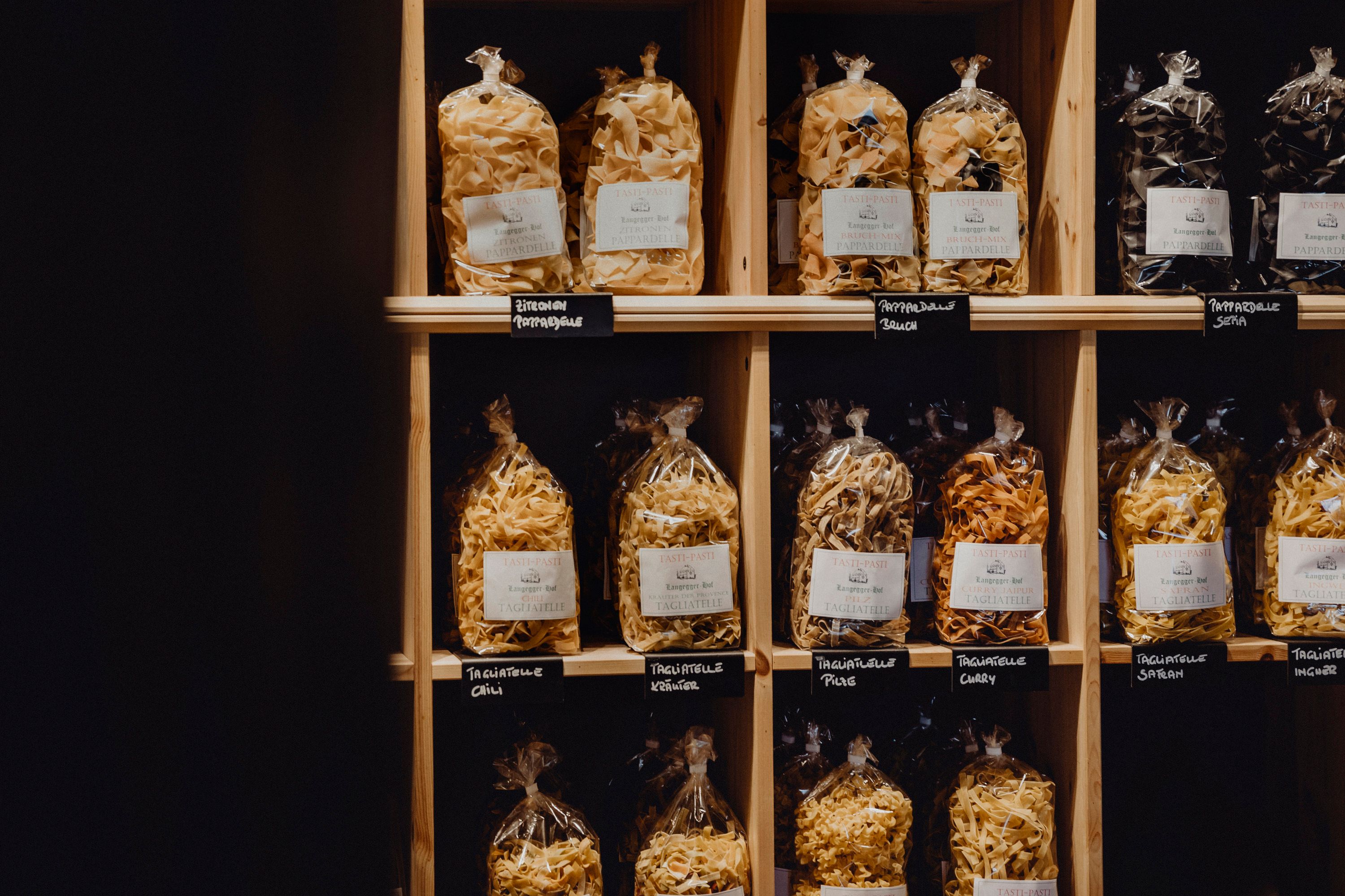 Shelf with different types of packaged pasta in bags.