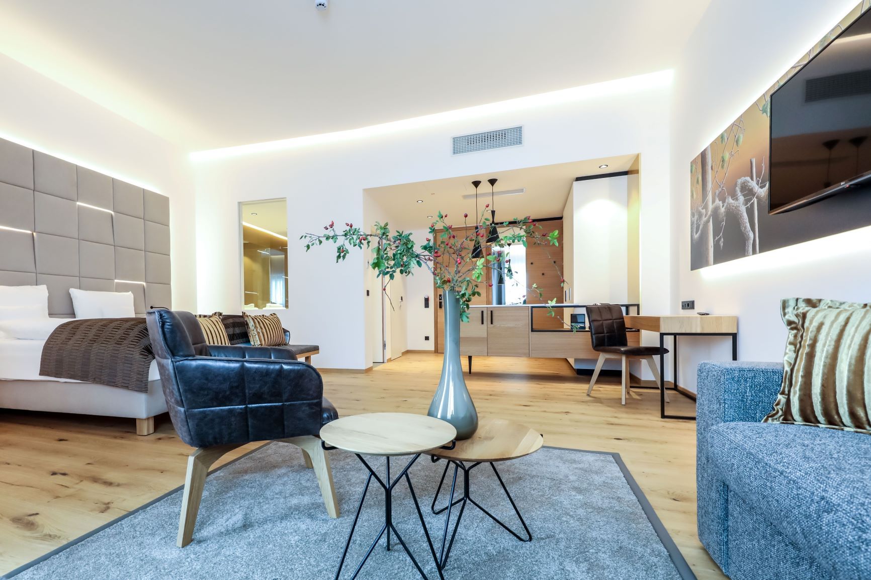 Modern furnished hotel room with bed, armchairs, table and decoration.