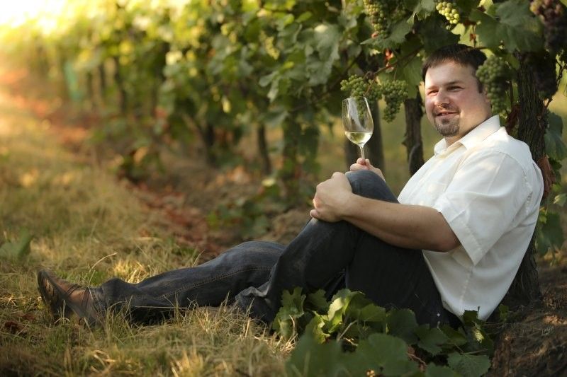 Man sitting in the vineyard with a glass of white wine.