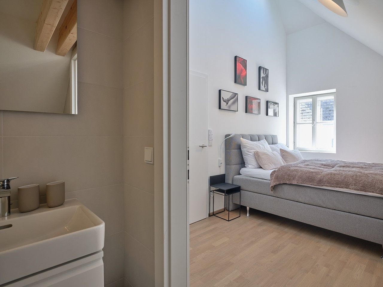 Modern bedroom with gray bed and adjoining bathroom.