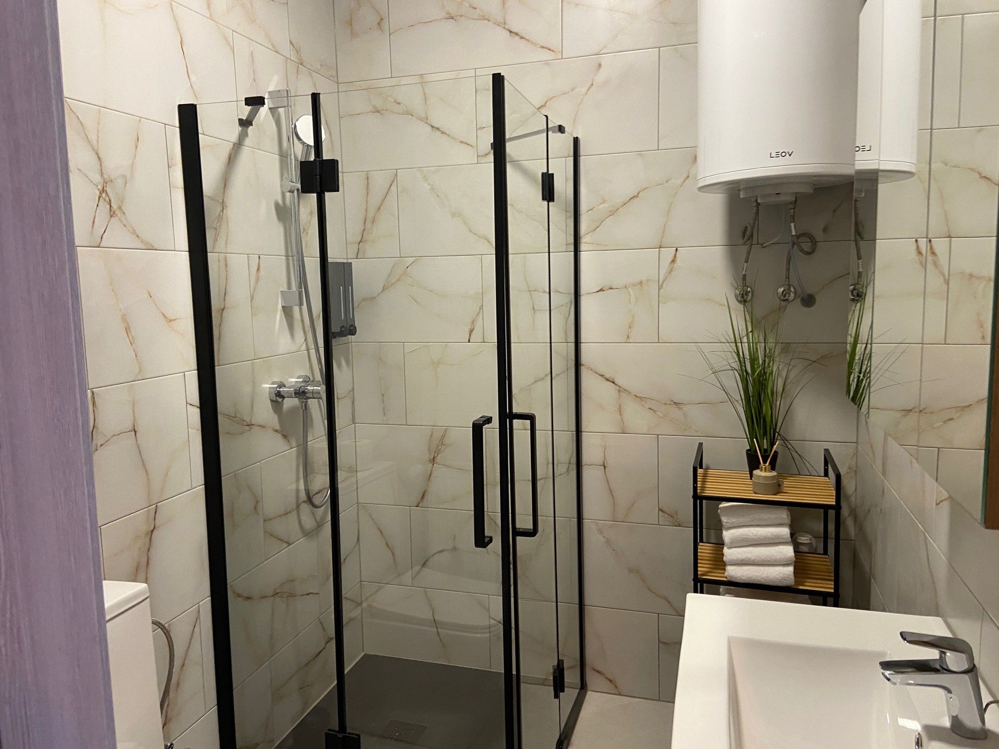 Modern bathroom with shower cubicle, washbasin and towel rack.