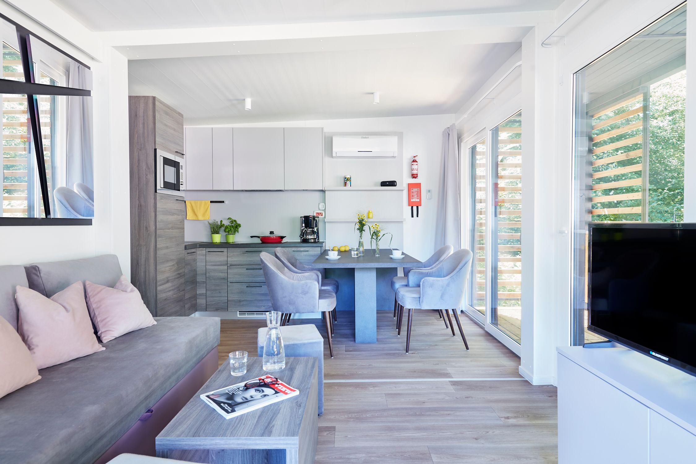 Mobile home from the inside with light-colored furniture and eat-in kitchen 