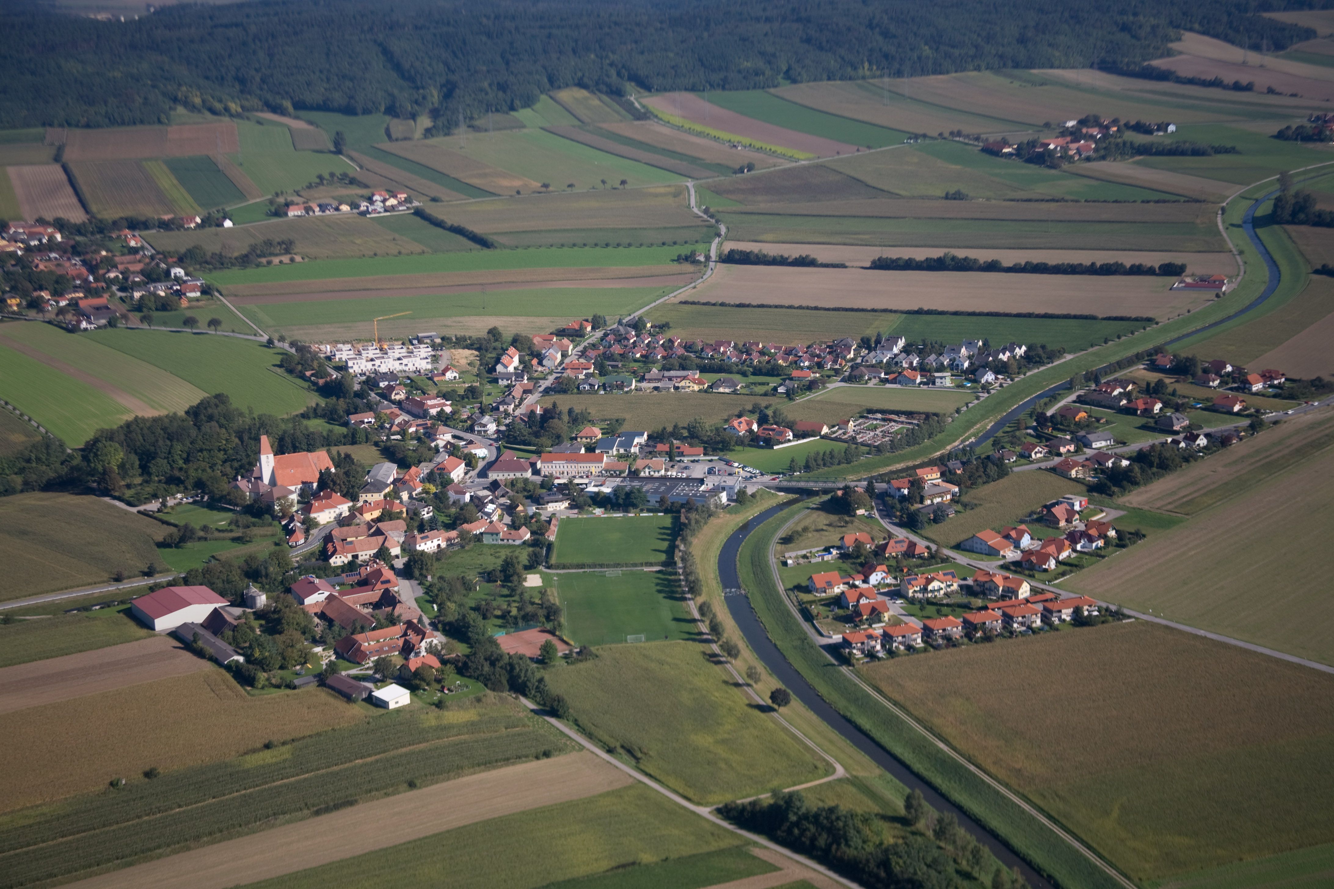 Aerial view of a village with surrounding fields and a river.