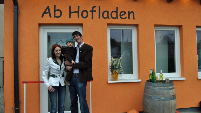Family in front of the Sch&auml;fer farm store in Maria Ellend, decorated with pumpkins and a wine barrel.