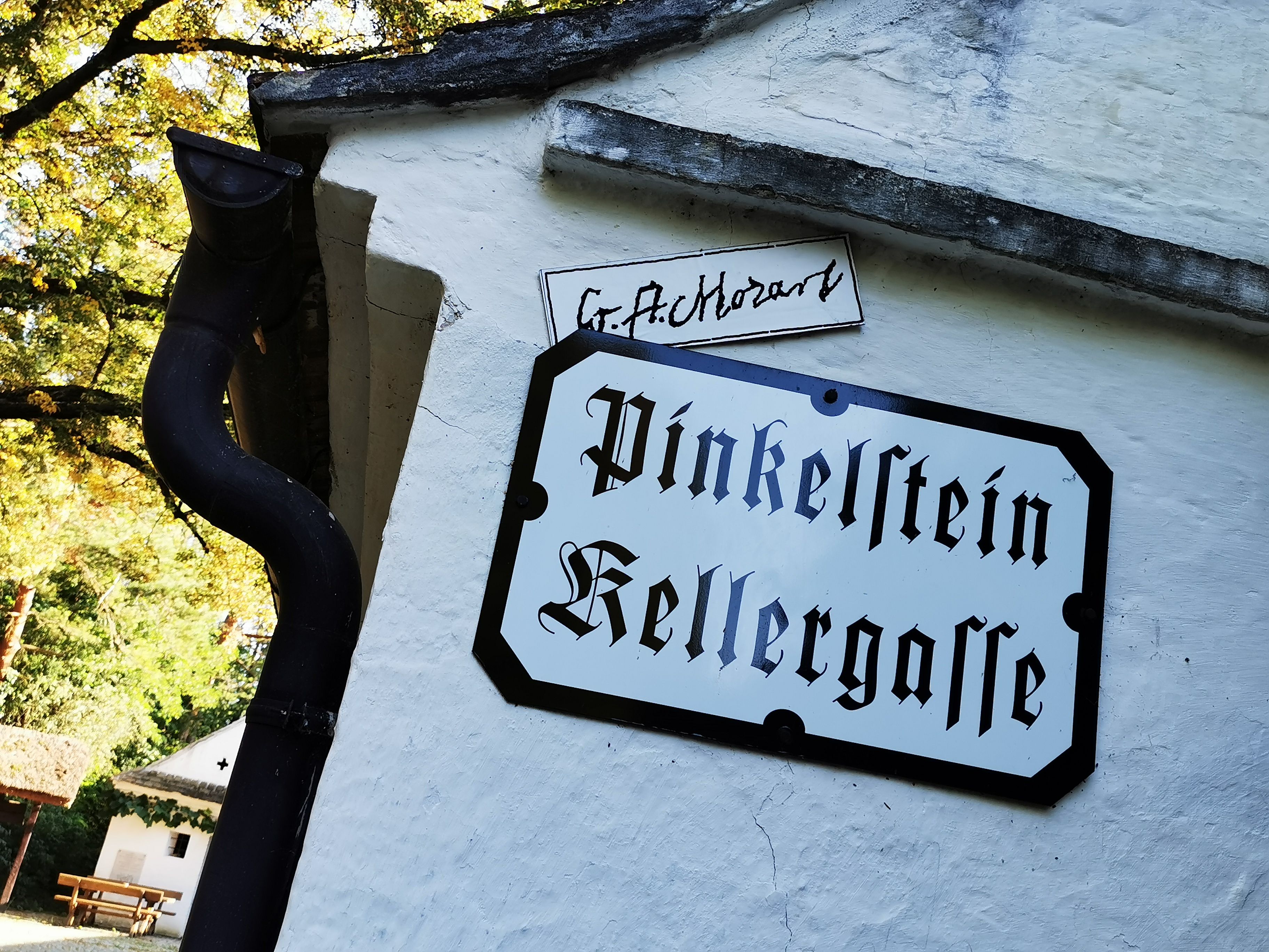 Sign with the inscription 'Pinkelstein Kellergasse' on a white wall.
