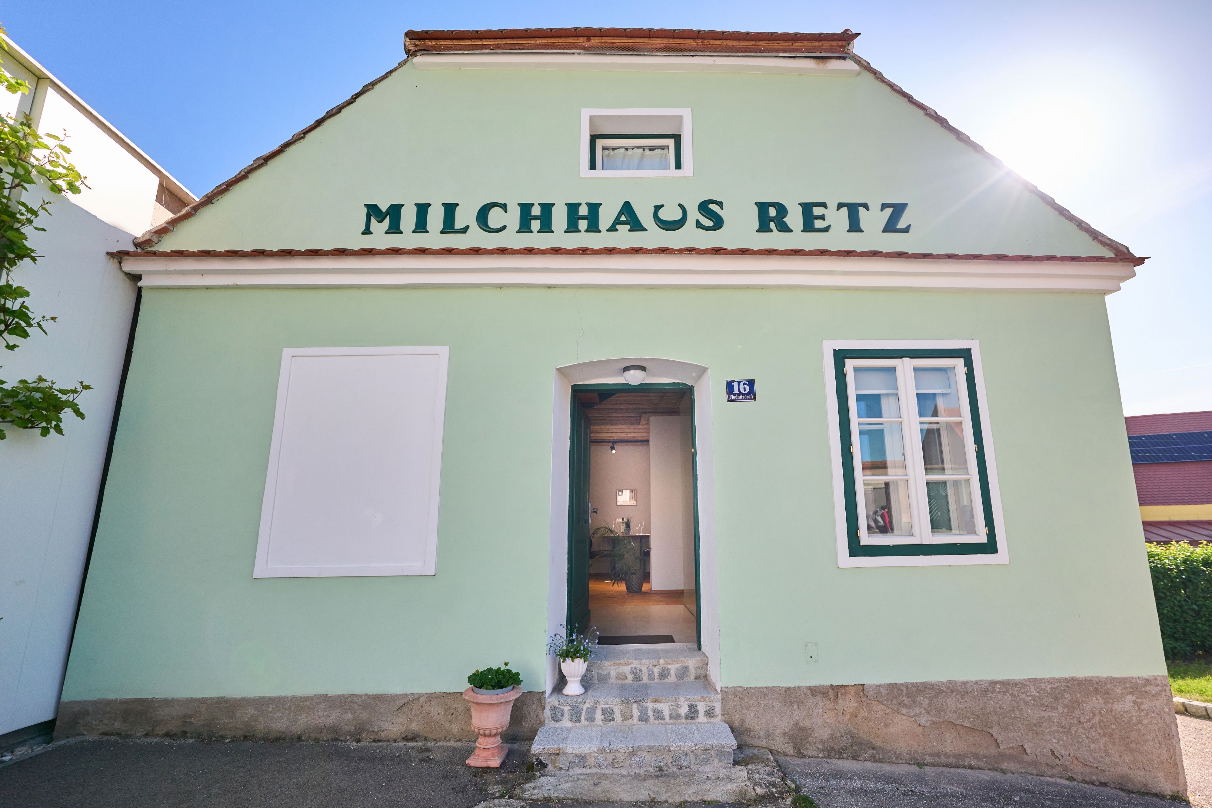 Green building with the inscription 'Milchhaus Retz' and an open door.