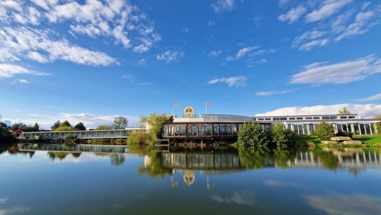 Exterior view of the cheese maker's world with blue sky and lake in the foreground.