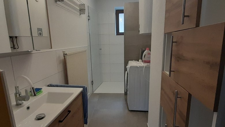 Modern bathroom with washbasin, shower and washing machine.