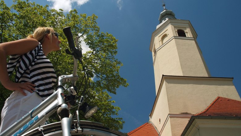 Woman with bicycle in front of the pilgrimage church Maria Moos.