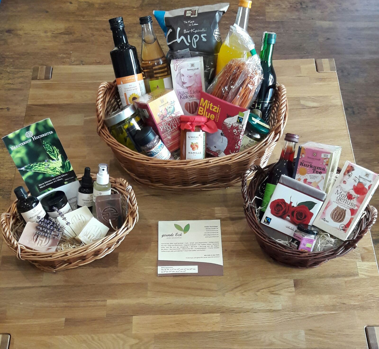 Three filled gift baskets on a wooden table.