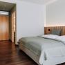Modern hotel room with double bed, wooden floor and desk.